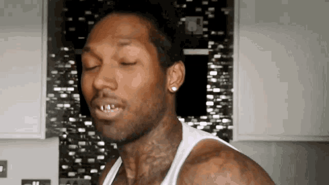 a man wearing a white tank top has a tattoo on his neck