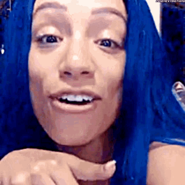 a close up of a woman with blue hair making a face .