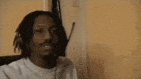 a man with dreadlocks is wearing a headset and smiling while sitting in a chair .