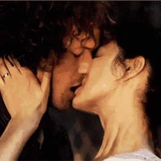 a man and a woman are kissing in front of a window .