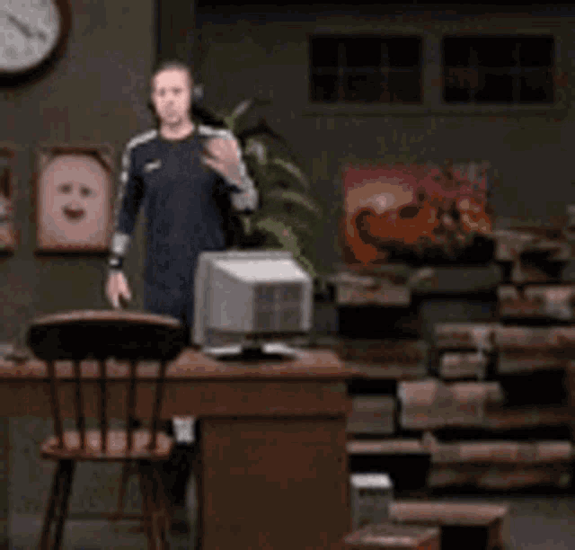 a man wearing headphones is standing in front of a computer in a room .