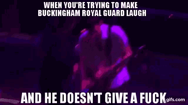 a man is playing a guitar and singing into a microphone in a dark room with purple lights .