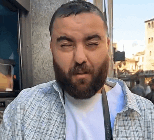 a man with a beard wears a fujifilm camera strap