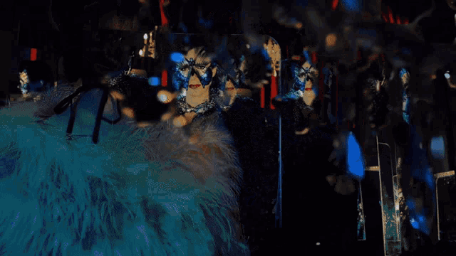 a woman wearing a butterfly mask and feathers stands in front of a mirror