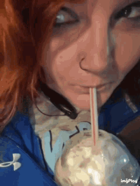 a woman with red hair drinking through a straw