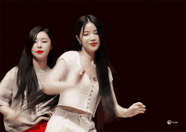 two women are dancing on a stage with a red curtain behind them and a sticker that says ' korean ' on it