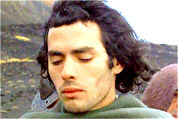 a man with long hair and a beard is looking down with his eyes closed