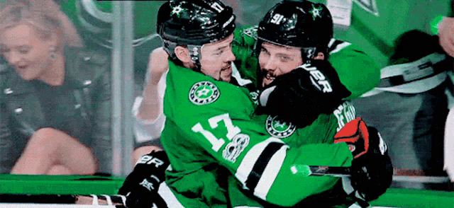 a hockey player with the number 17 on his jersey hugging another hockey player