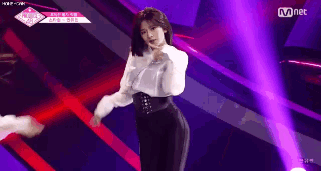 a woman in a white shirt and black pants is dancing on stage .