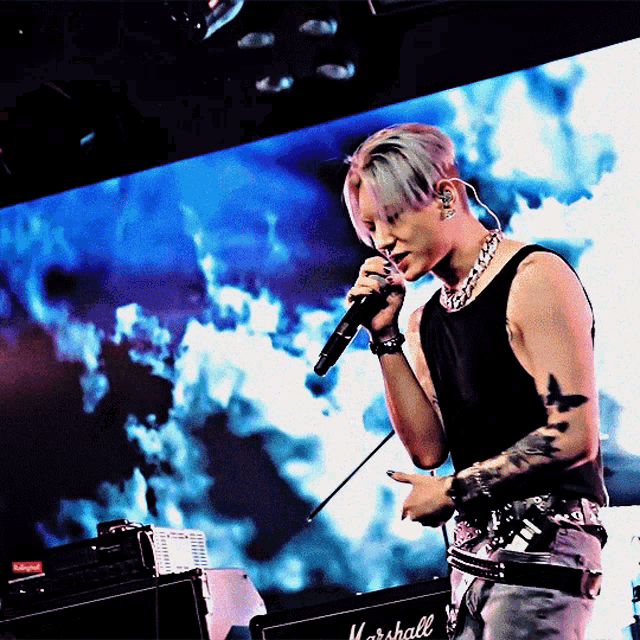 a man is singing into a microphone in front of a marshall amplifier