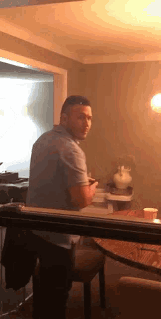 a man is sitting at a table in a room looking at his phone .