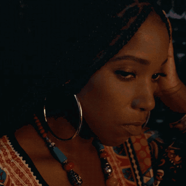 a close up of a woman wearing hoop earrings and a necklace with the letter a on it