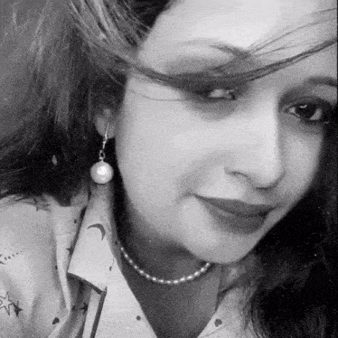 a black and white photo of a woman wearing pearl earrings and a pearl necklace