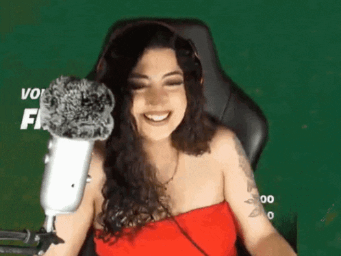 a woman in a red dress is smiling in front of a microphone .