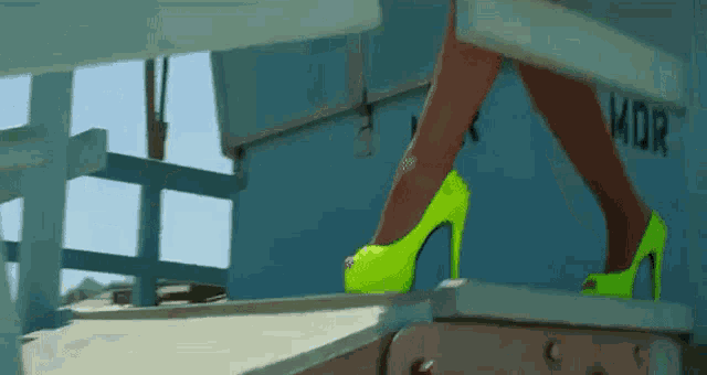 a woman wearing neon green high heels is walking down stairs .