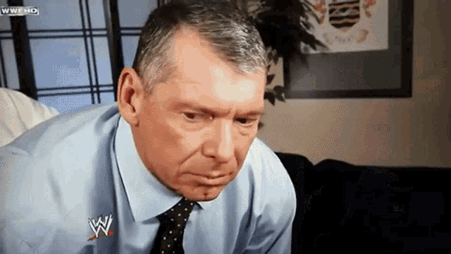 a man wearing a blue shirt and tie with a wwe logo on his shirt