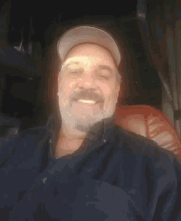 a man wearing a hat and a blue shirt is smiling for the camera