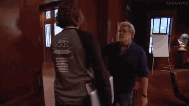 two men are fighting in a room and one of them is holding another man 's arm .