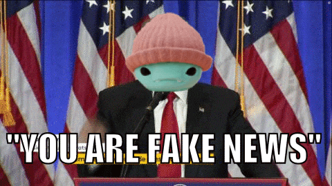 a man in a suit and tie stands at a podium with the words " you are fake news " written above him
