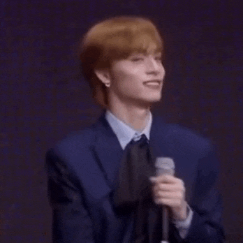 a man in a suit and tie is holding a microphone and clapping .