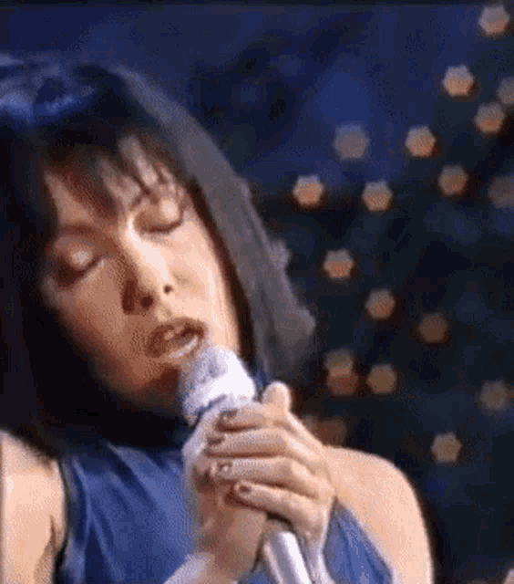 a woman singing into a microphone in front of a christmas tree