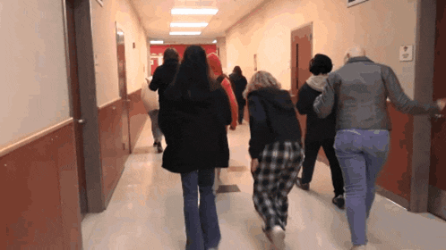 a group of people walking down a hallway with a sign that says exit