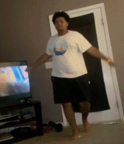 a man in a white shirt with a boat on it is dancing in front of a television