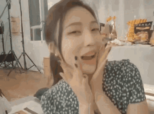 a woman in a green dress is making a funny face with her hands .
