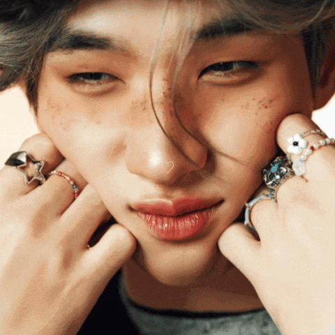 a close up of a man 's face with rings on his fingers