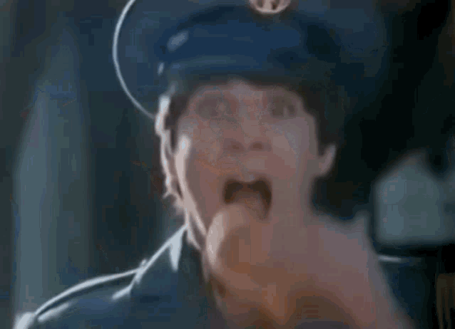 a close up of a police officer making a funny face while wearing a blue hat .
