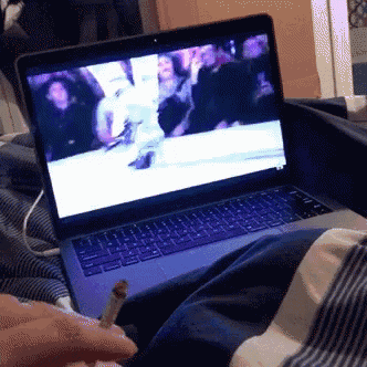 a person is smoking a cigarette in front of a laptop computer