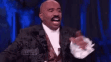 a man in a suit and tie is laughing with his arms outstretched .