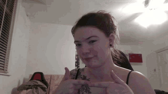 a woman with a tattoo on her chest is making a peace sign