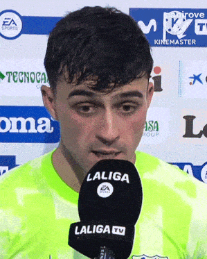 a man speaking into a laliga tv microphone while wearing a neon green shirt