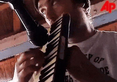 a man is playing a keyboard and singing into a microphone while wearing a tie .