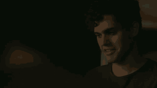 a close up of a man 's face in a dark room looking at the camera .