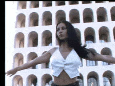 a woman with her arms outstretched in front of a building with arches