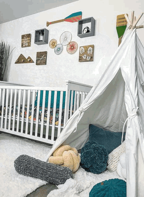 a baby 's nursery with a teepee , crib , and pillows .