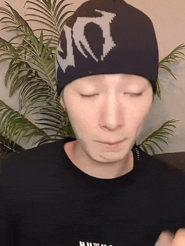 a man wearing a black shirt and a black beanie with the letter d on it