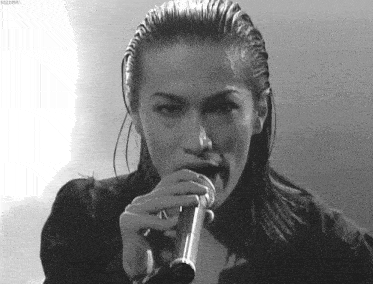a black and white photo of a woman singing into a microphone