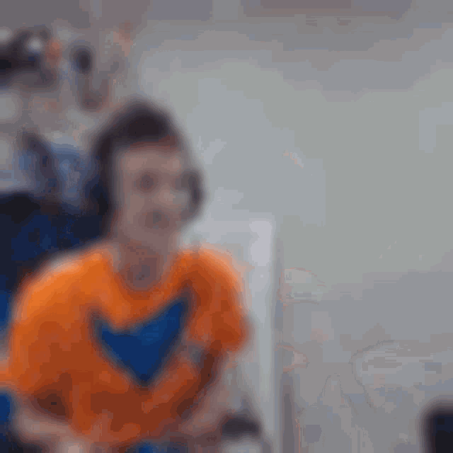 a man wearing headphones and an orange shirt is sitting in a chair .