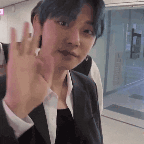 a man with blue hair is waving his hand