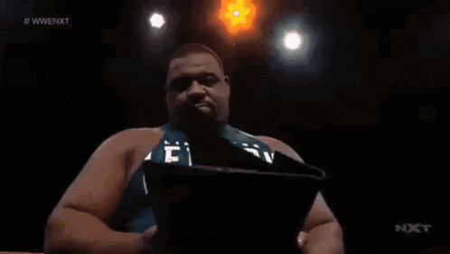 a person is holding a picture of a wave in front of a sign that says wwe nxt