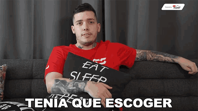 a man sitting on a couch holding a pillow that says eat sleep