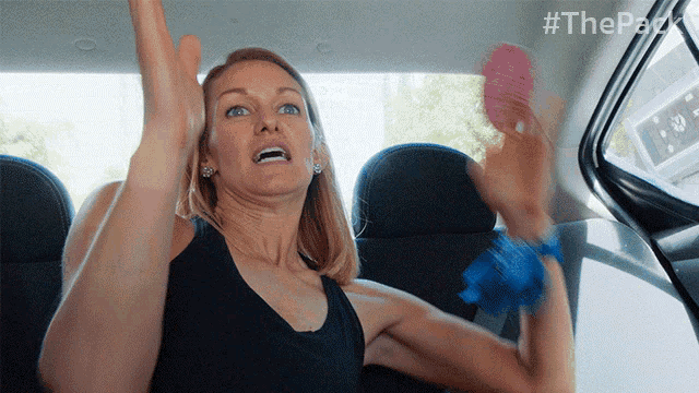 a woman sitting in the back seat of a car with her arms in the air with the hashtag #thepack