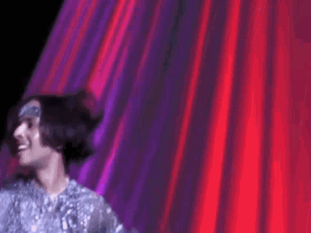 a blurry picture of a woman dancing in front of a red curtain