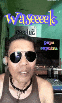 a man wearing sunglasses stands in front of a tv screen that says papa saputra on it
