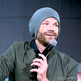 a man wearing a beanie is holding a microphone in his right hand