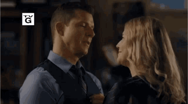 a man and a woman are hugging and smiling in front of a sign that says hallmark movies & mysteries