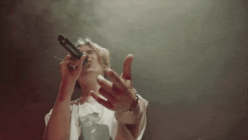 a person singing into a microphone with smoke coming out of their mouth